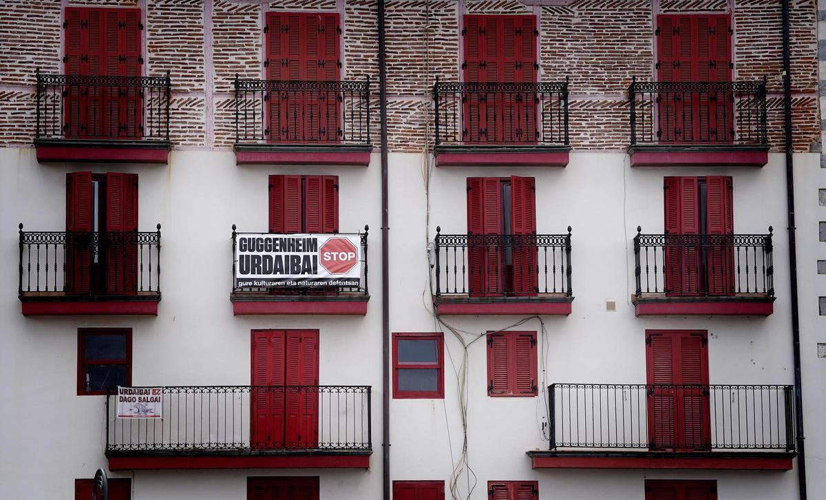Vista de una fachada de apartamentos en Mundaka, con un cartel en contra de la ampliación del Museo Guggenheim en la Reserva de la Biosfera de Urdaibai.
