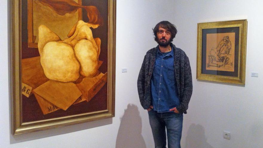 José García Chillerón, comisario de la exposición, posa con dos cuadros de su padre.