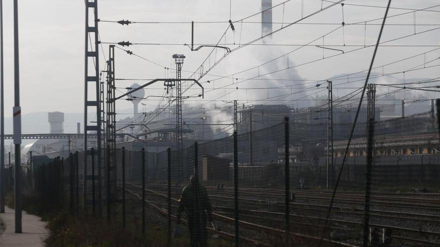 Un hombre camina por las vías del tren, junto al Puerto de Avilés.