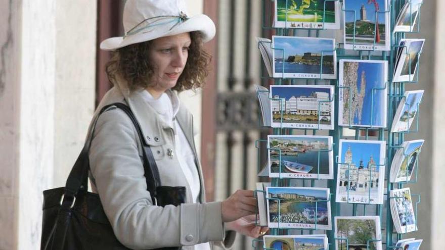 Una mujer observa varias postales de la ciudad de A Coruña.