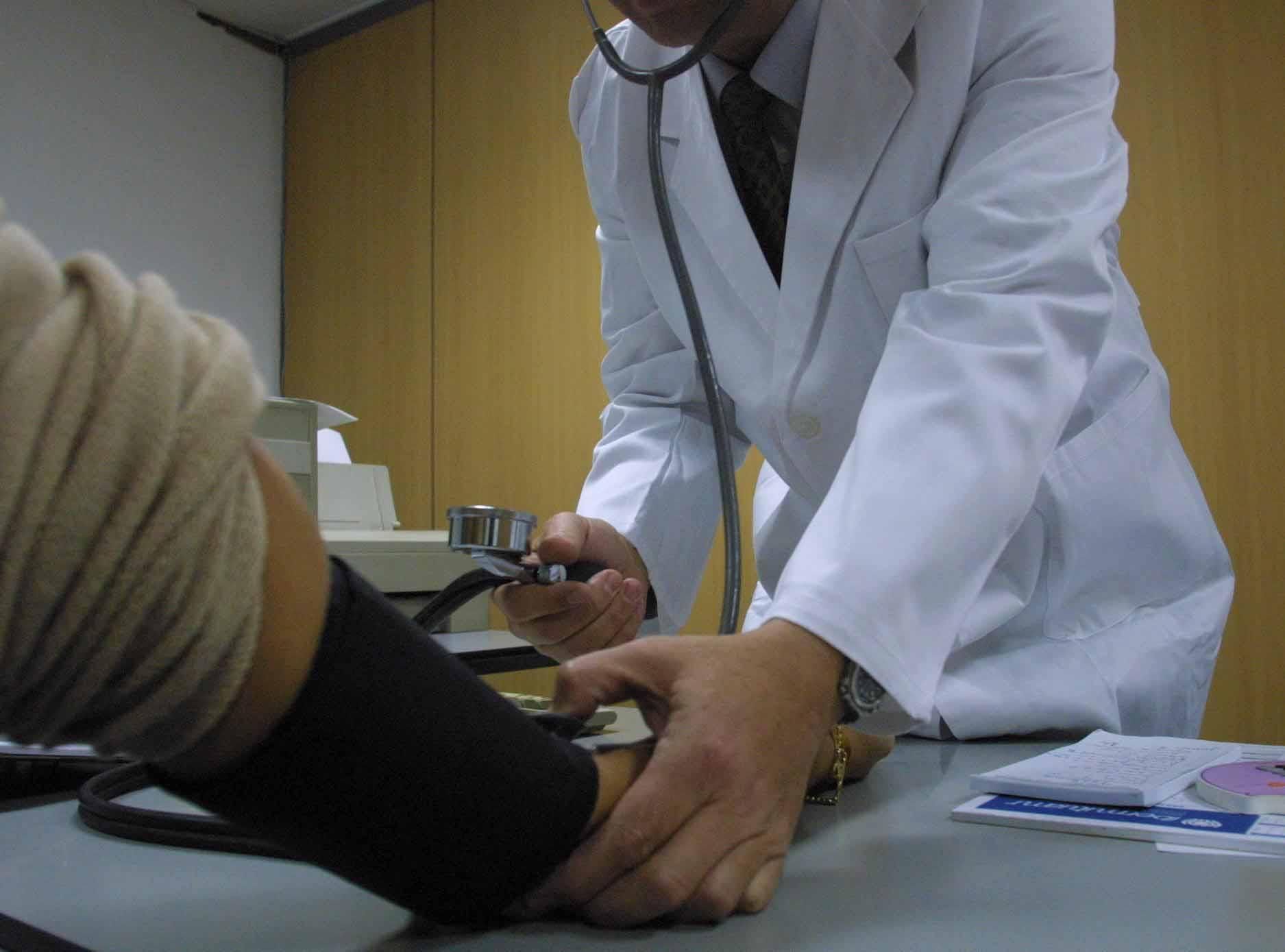 Un médico mide la tensión a un paciente en la consulta. l.O.