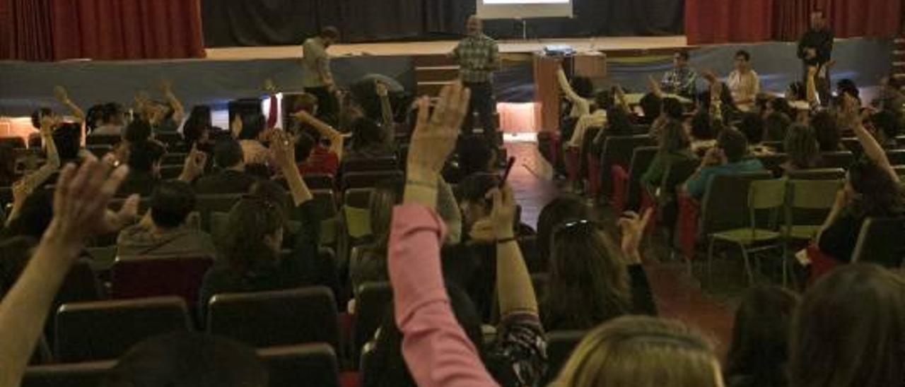 Padres con el brazo en alto para preguntar dudas sobre la jornada continua en una reunión informativa