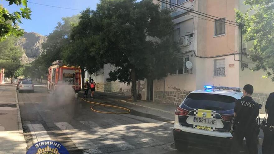 Los bomberos sofocando las llamas bajo la vigilancia de la Policía Local en El Poblao de Villena.