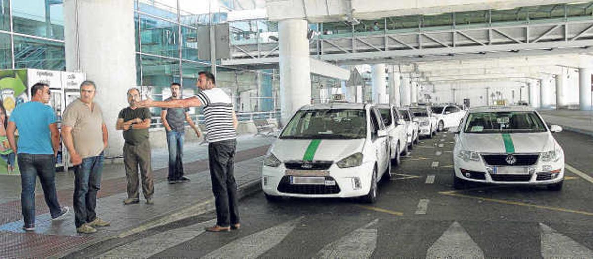 Algunos taxistas de Elche, junto a sus vehículos en la parada que tienen habilitada en el aeropuerto de El Altet.