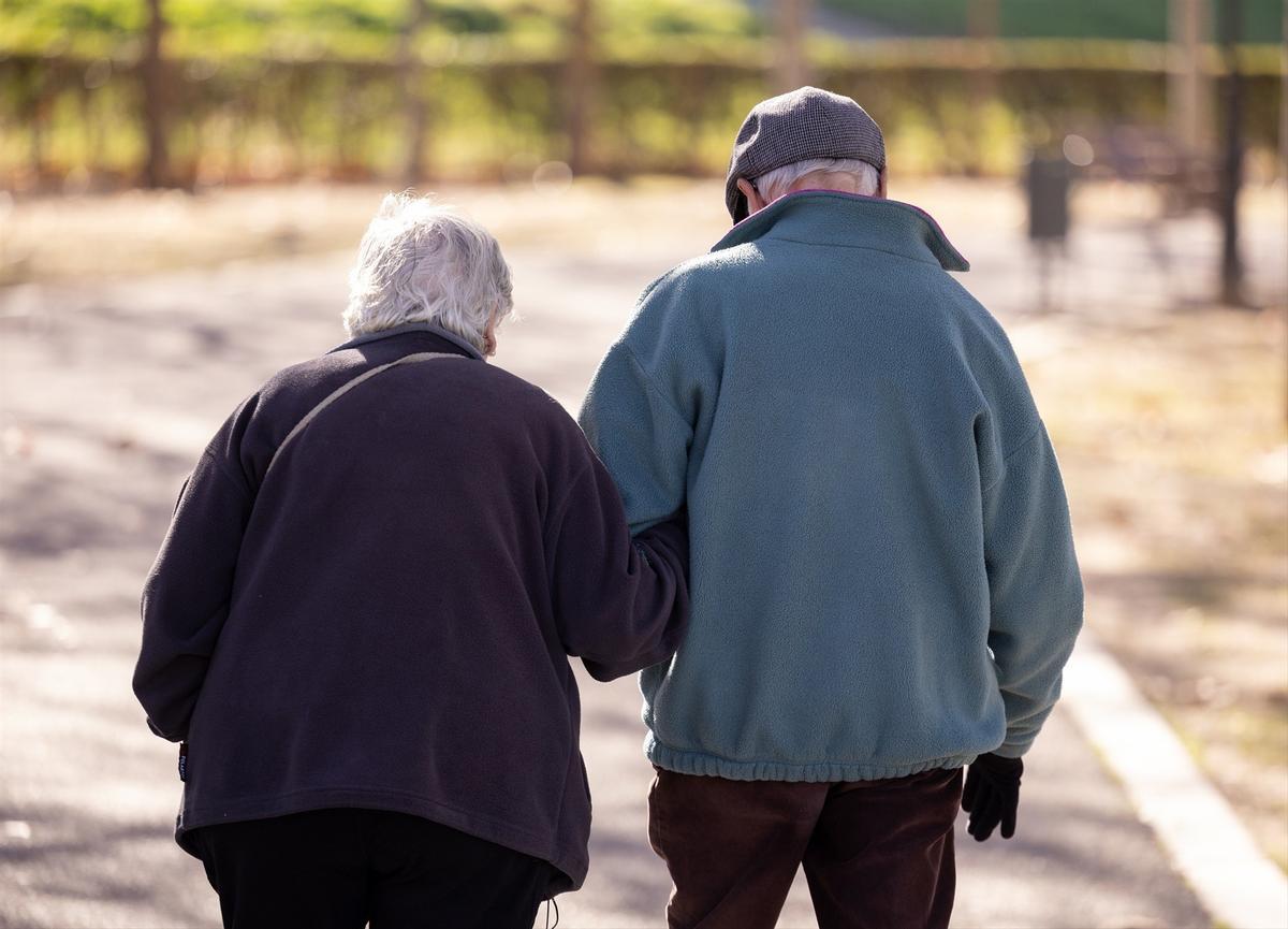 Dos personas mayores caminando por la calle.