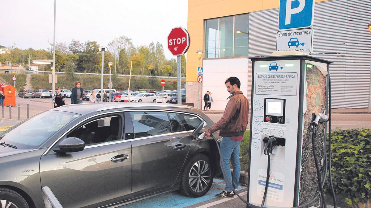 Un home carregant el seu vehicle híbrid a l'únic carregador públic que queda a Girona, davant del Ocines