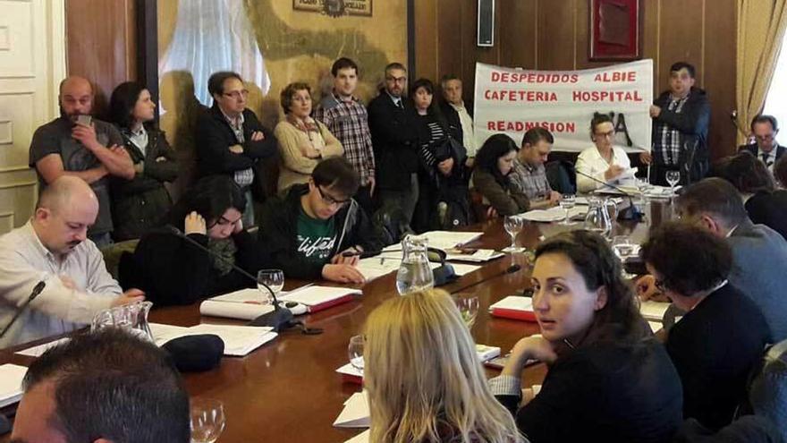 Los trabajadores despedidos, portando una pancarta, en el Pleno de Mieres.