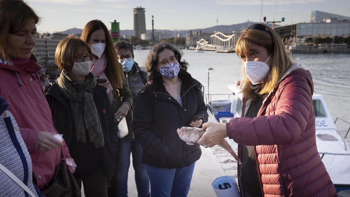 La bióloga Anna Bozzano enseña un pez rata recién capturado a las visitantes del Moll de Pescadors.