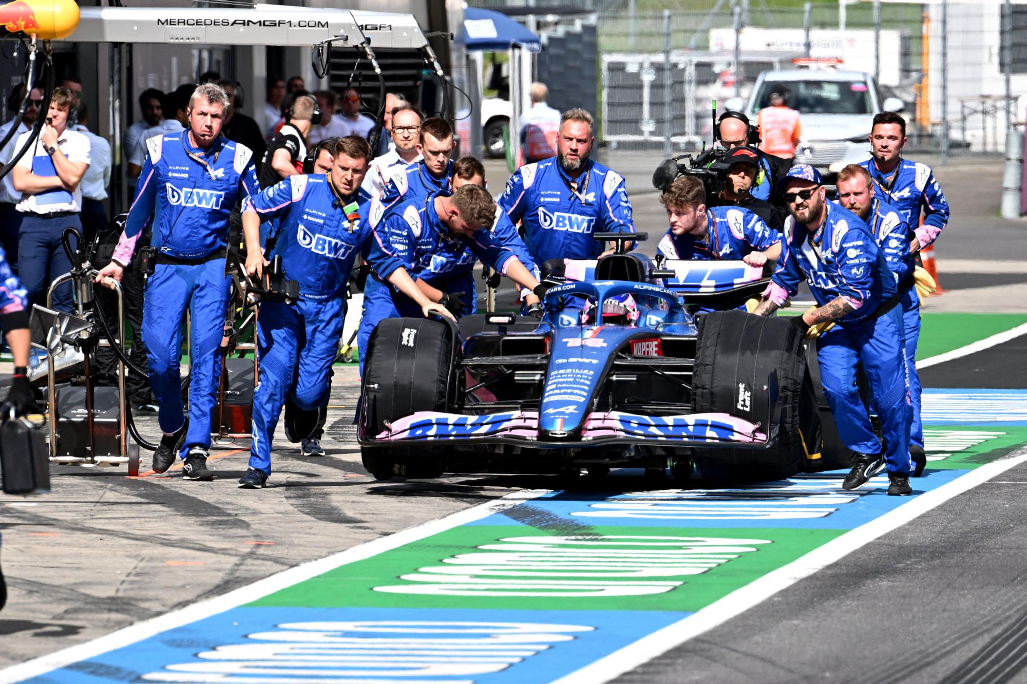 Los mecánicos de Alpine empujan el coche de Fernando Alonso.