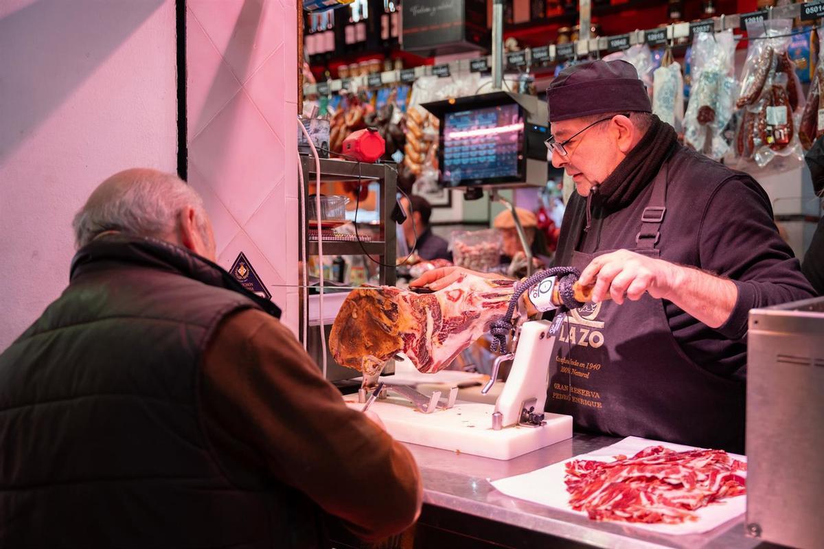 Un autónomo atendiendo a un cliente en su puesto de un mercado de abastos.