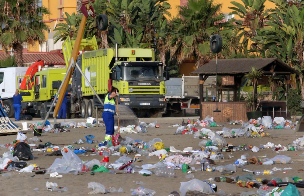 Los operarios de los servicios de limpieza trabajan para dejar la playa en óptimas condiciones tras una larga noche de fiesta en la arena