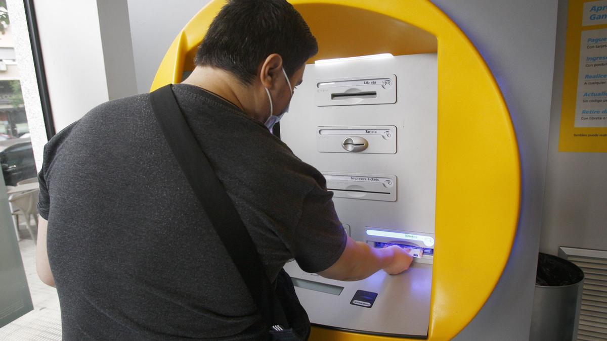 Un vecino de Zaragoza saca dinero en efectivo del cajero de su banco.
