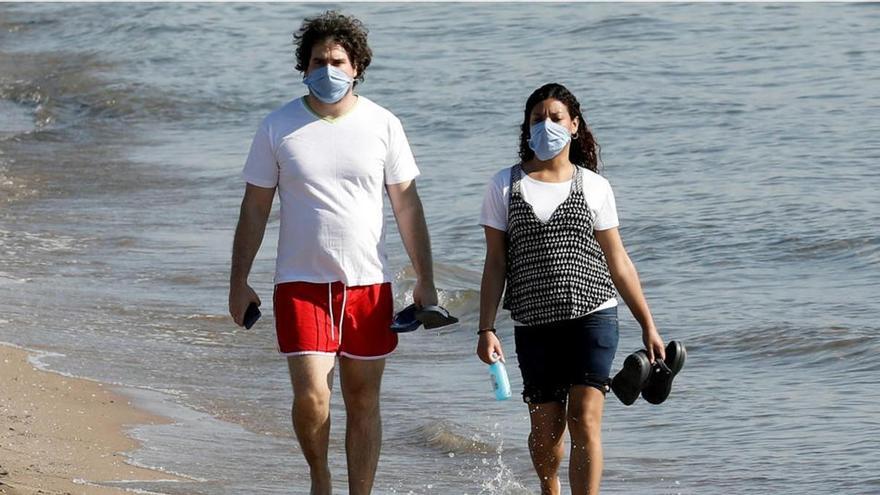 Una pareja pasea por una playa durante la desescalada.