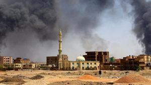 Un hombre camina hacia las columnas de humo provocadas por un bombardeo aéreo después de un bombardeo en Jartum.