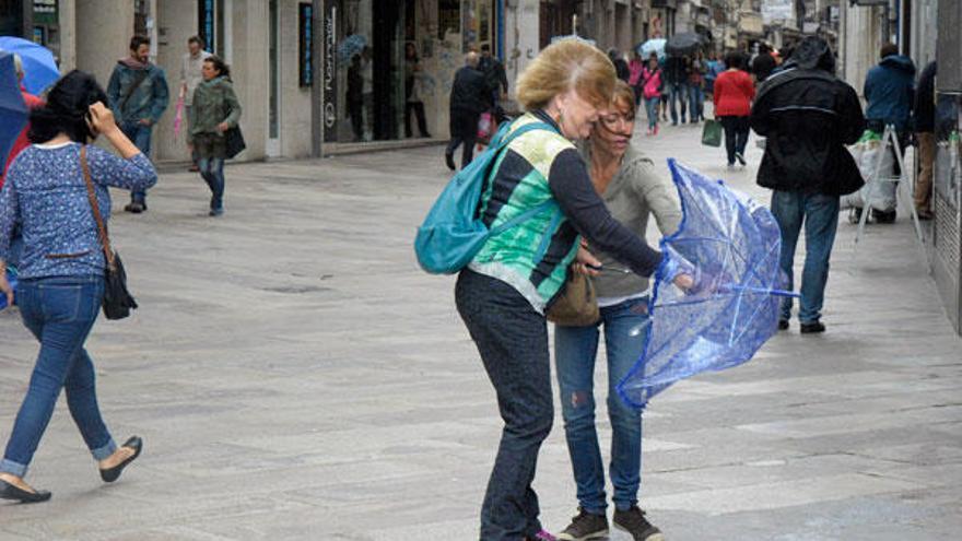 Dos mujeres sujetan un paraguas en A Coruña.