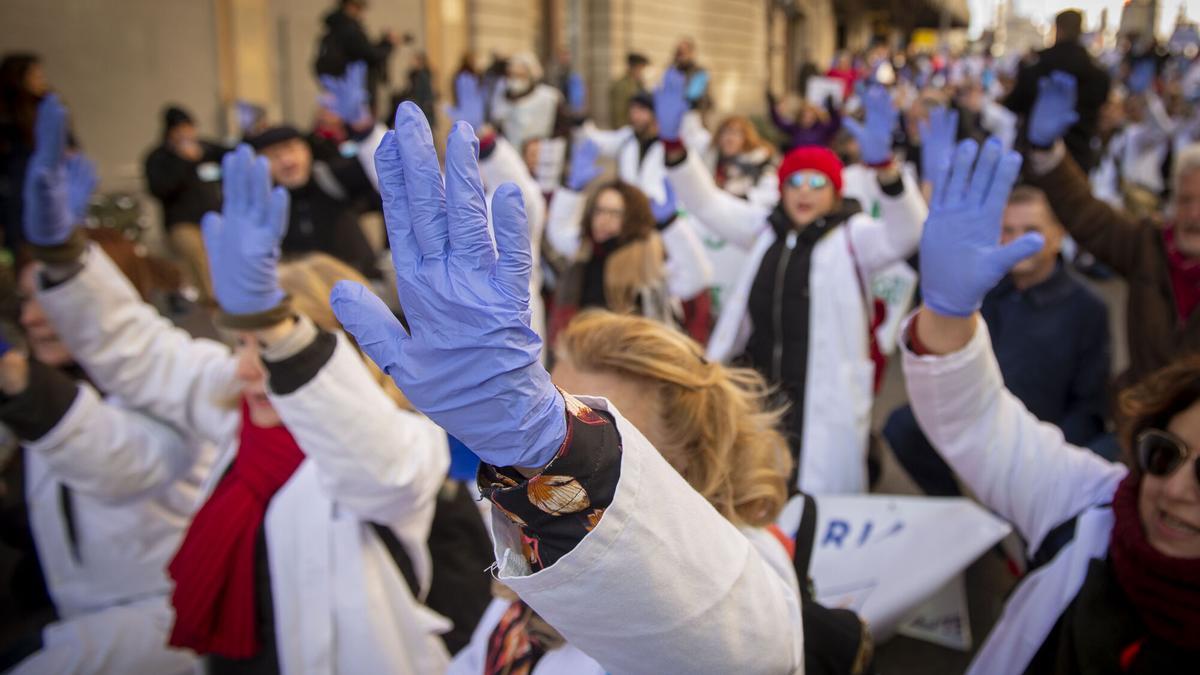 Varias personas con batas blancas y guantes azules protestan durante una marcha convocada por médicos y pediatras de Atención Primaria (España).