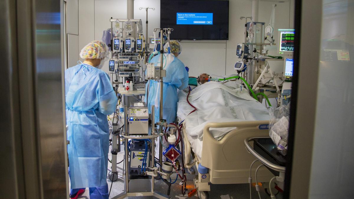 Un sanitario asiste a un enfermo de covid-19, en la uci del Hospital Clínic de Barcelona.