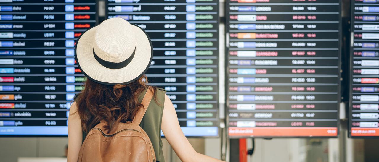 Imagen de una pasajera viendo el panel de vuelos en un aeropuerto de las Islas.