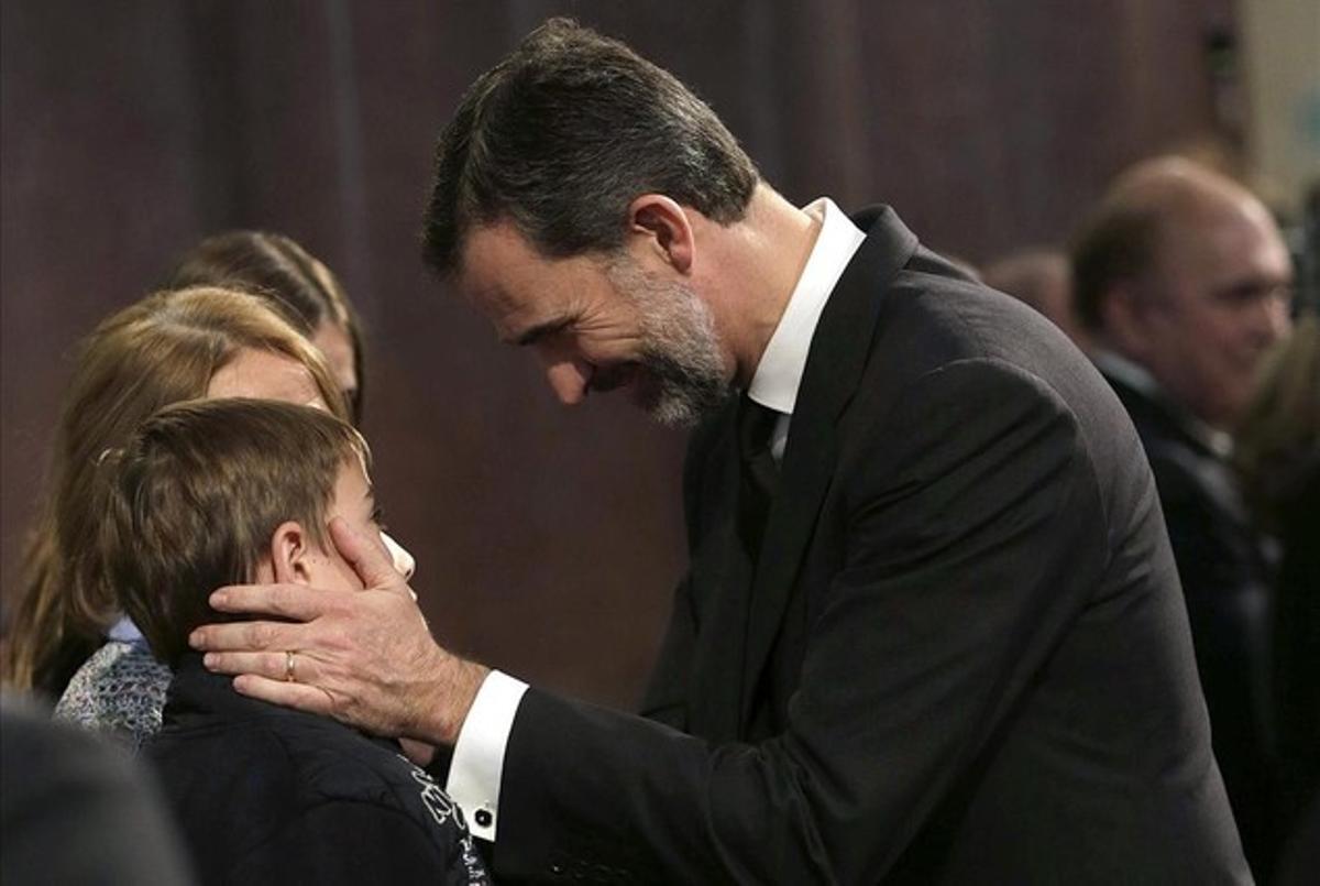 El rey Felipe consuela a un niño durante el funeral institucional celebrado en la basílica de la Sagrada Familia