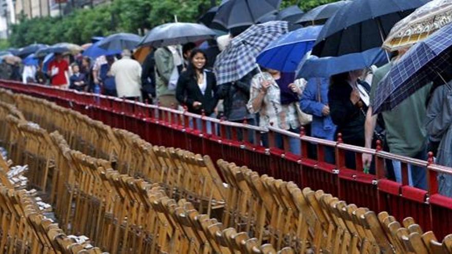 Los turistas pasan por delante de una de las tribunas colocadas para ver las procesiones.