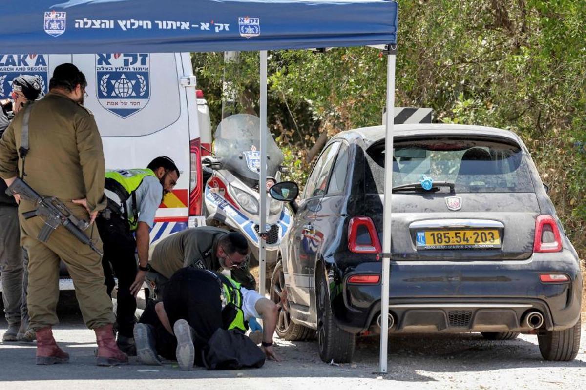 Miembros del servicio de emergencias de Israel inspeccionan el vehículo de una víctima del tiroteo este domingo en Tzur Yitzhak.