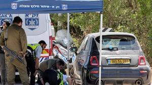 Miembros del servicio de emergencias de Israel inspeccionan el vehículo de una víctima del tiroteo este domingo en Tzur Yitzhak.