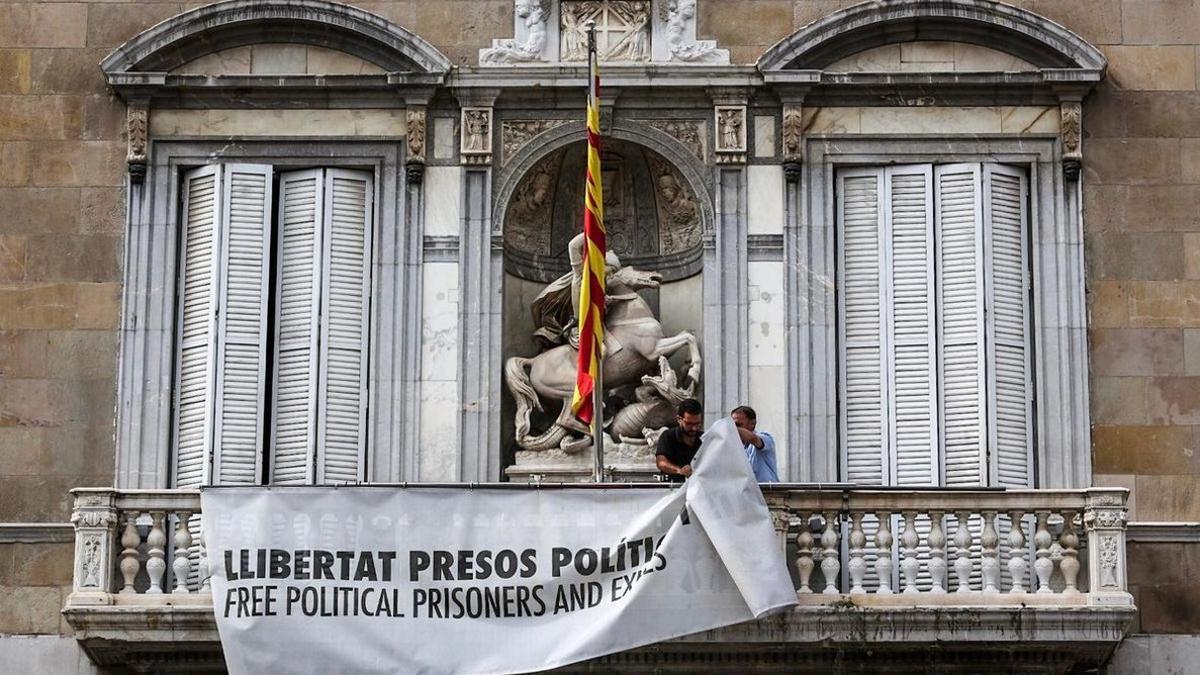 Dos trabajadores de la Generalitat retiran la pancarta.