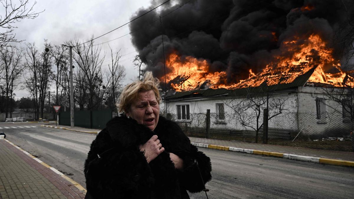 Una mujer reacciona frente a una casa en llamas después de ser bombardeada en la ciudad de Irpin, en las afueras de Kiev,