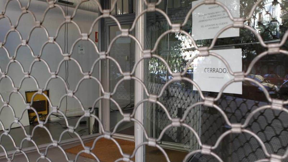 Establecimiento con la verja bajada y un cartel de 'cerrado'.