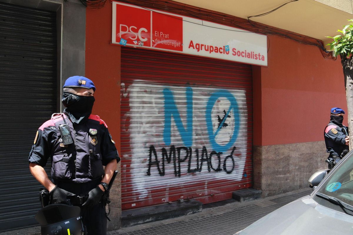 Els Mossos d’Esquadra custodien la seu del PAC al Prat de Llobregat, on hi ha una pintada contra l’ampliació de l’aeroport.
