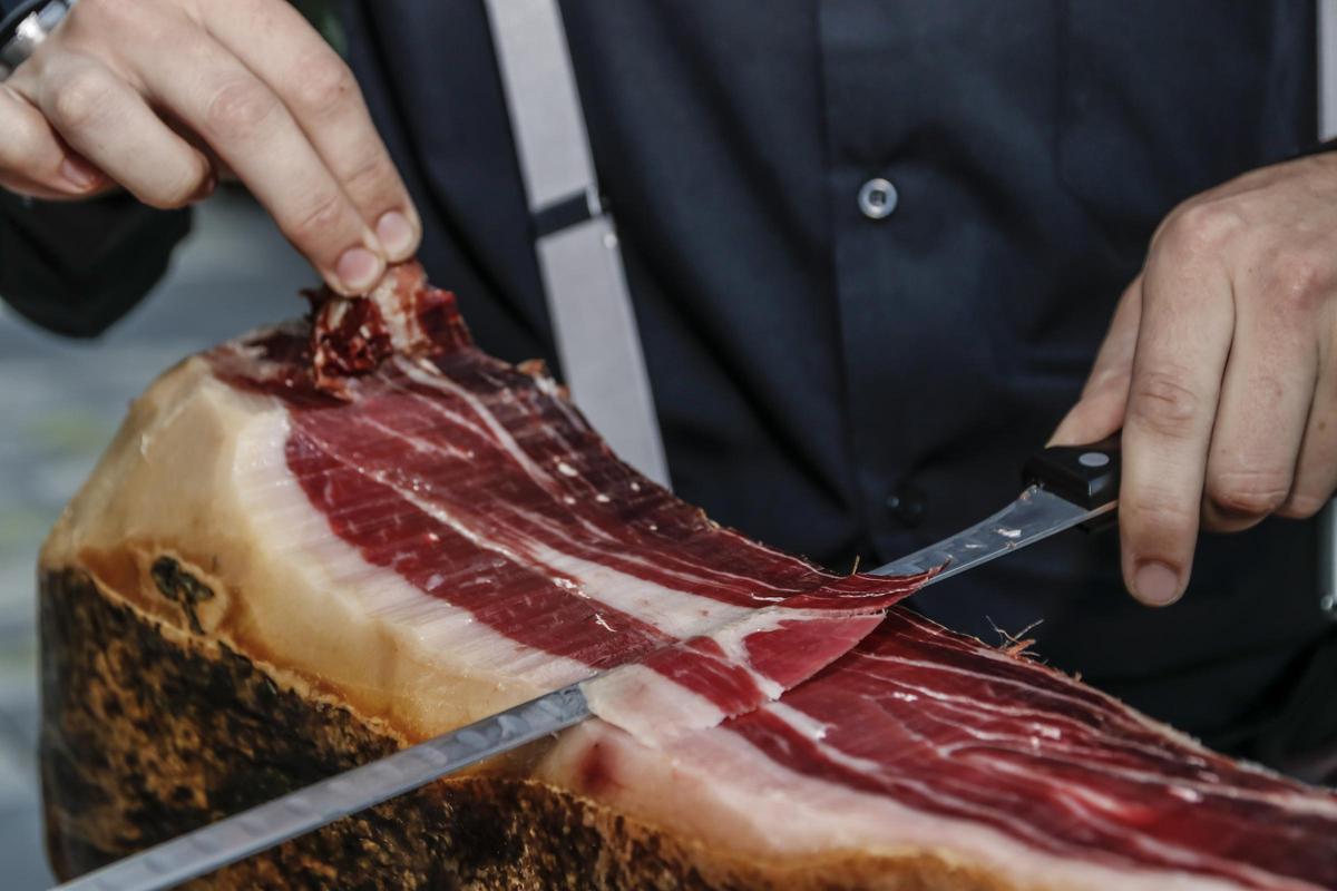Un maestro cortador  lonchea un jamón ibérico extremeño.