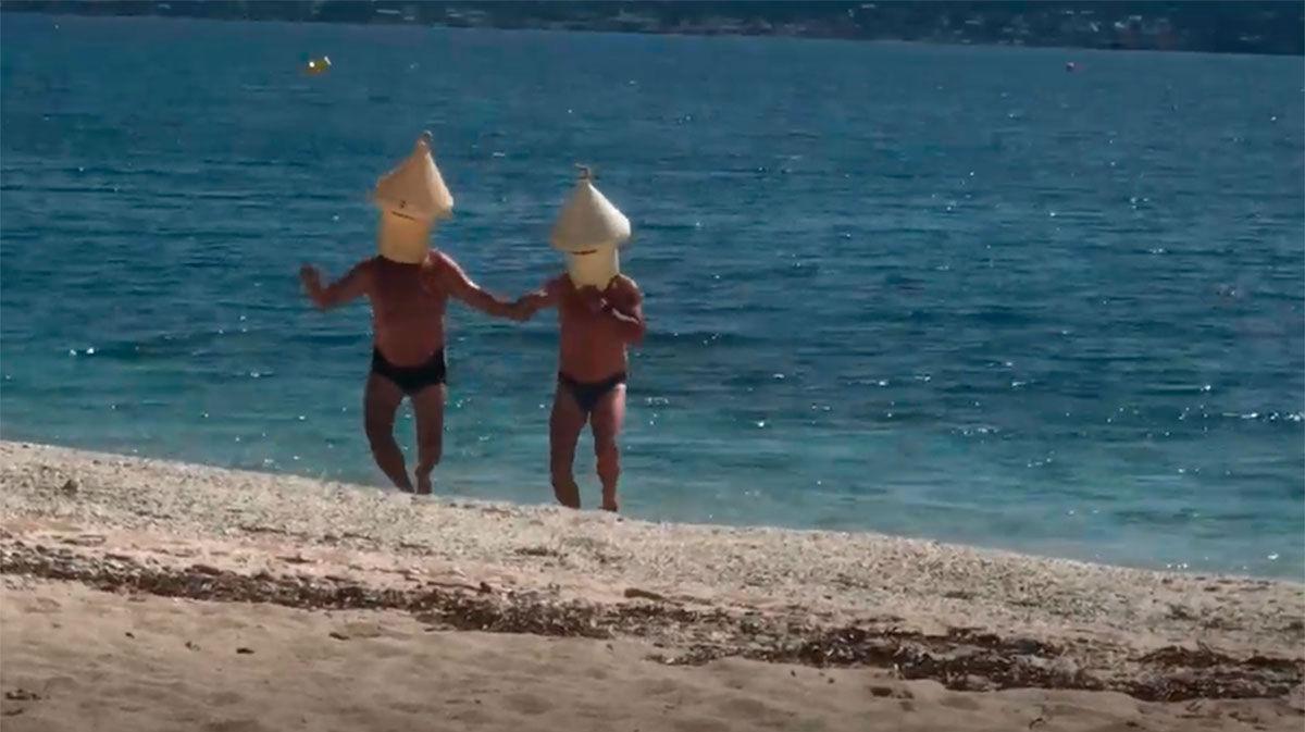Dos personas se bañan en la playa disfrazados de boya