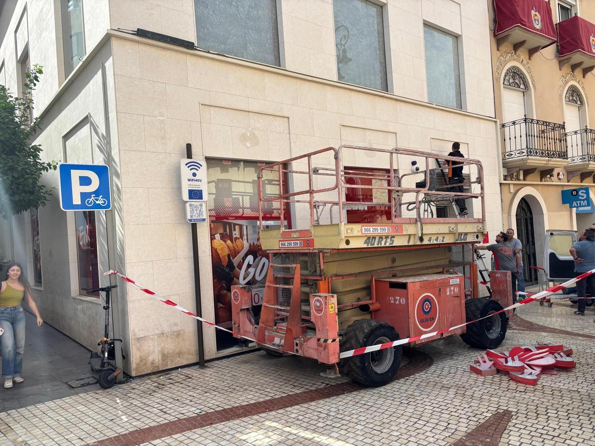 Operarios retiraban hace unos días los carteles del Banco Santander de la Plaça de Baix en Elche
