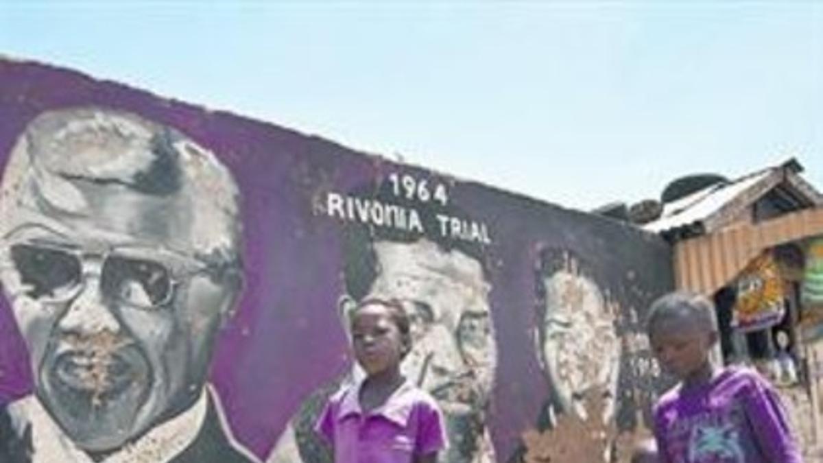 Unos niños caminan frente a un mural de Mandela, ayer en Soweto.