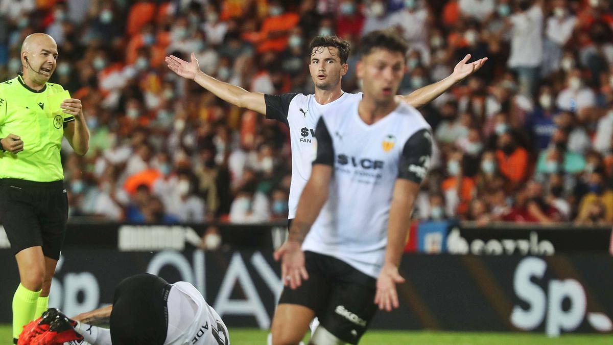 Los jugadores del Valencia protestan una decisión arbitral, con Maxi Gómez en el suelo. | F. CALABUIG