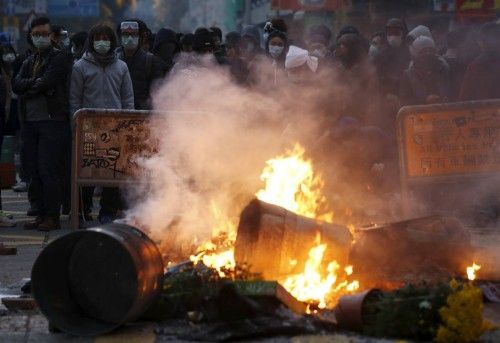 Protesters look on behind a fire set by them at a junction at Mongkok district in Hong Kong