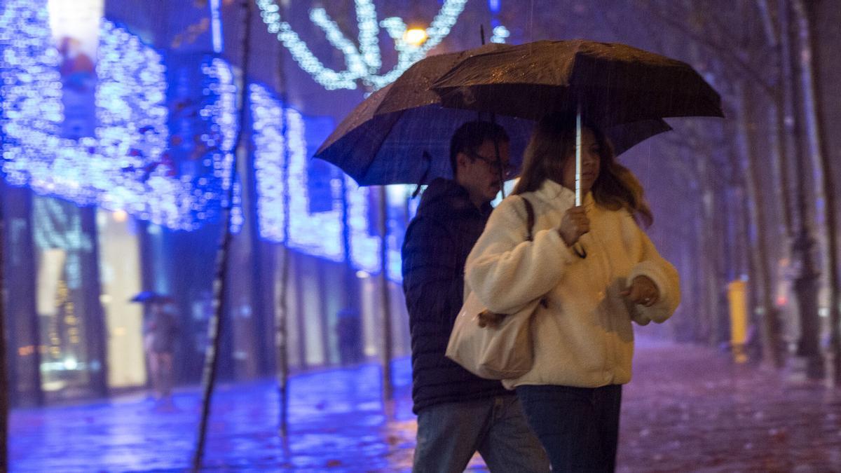 Dos personas que se refugian bajo el paraguas en Barcelona