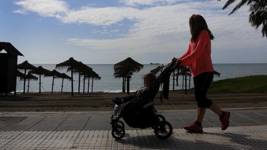 Una mujer pasea con su hija por el paseo marítimo de la playa de la Malagueta.