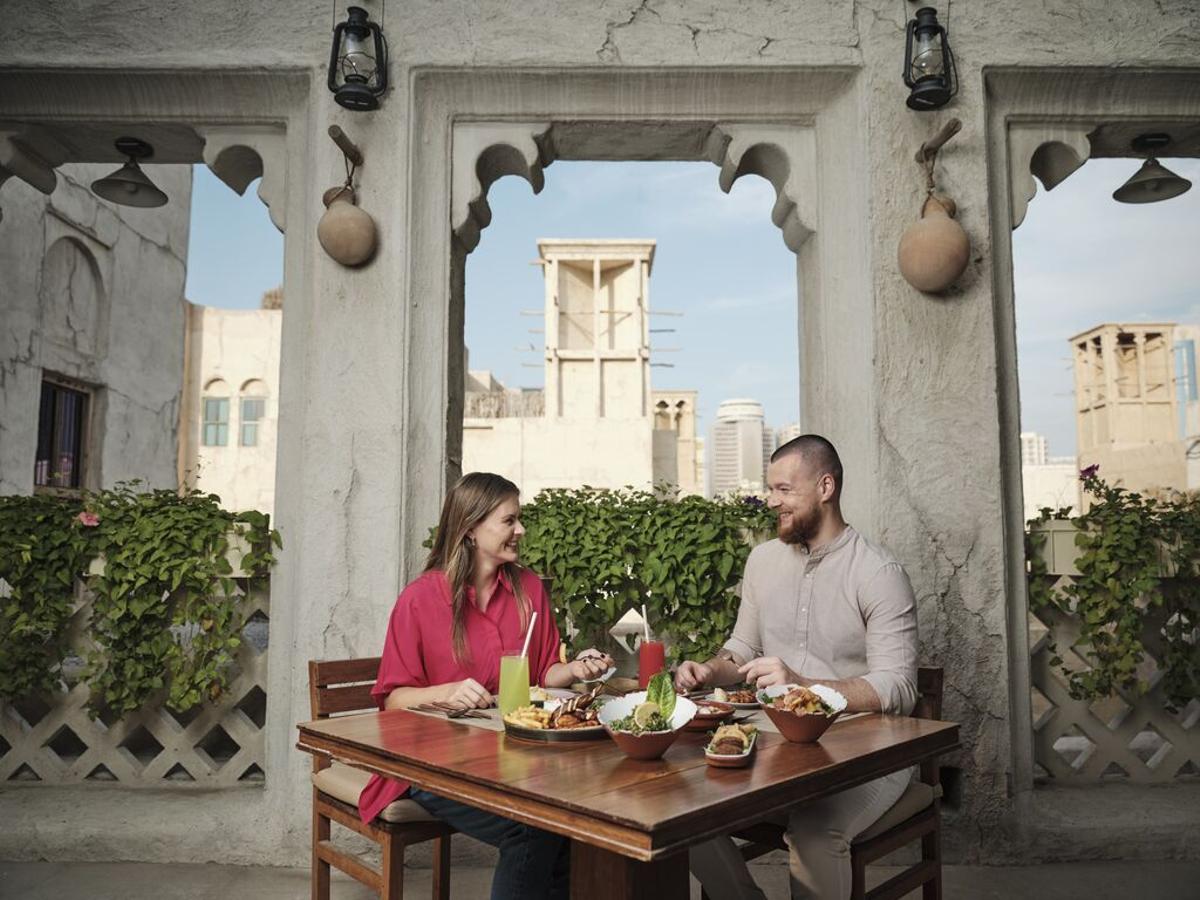 Pareja comiendo en Al Seef Heritage Hotel, un lugar perfecto para descubrir las raíces de Dubái y los auténticos Emiratos