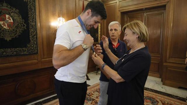 Abel Serdio, jugador olímpico de balonmano, enseña la medalla a Mariví Monteserín, alcaldesa de Avilés, durante la recepción. | Ricardo Solís