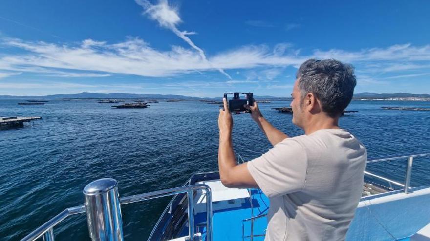 Un hombre fotografía las bateas en aguas de O Grove a bordo de un barco de pasaje que realiza un recorrido por la ría