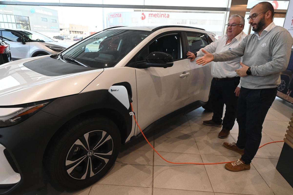 Dos hombres observan las características de un vehículo eléctrico en un concesionario de Castellón.