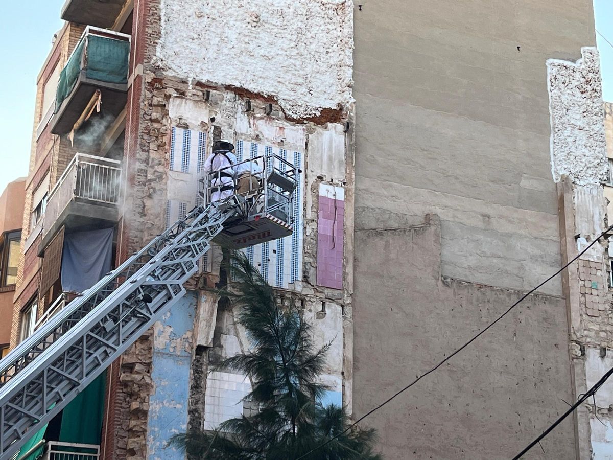 Dos apicultores subidos en la grúa de un camión de bomberos actúan sobre la zona afectada.