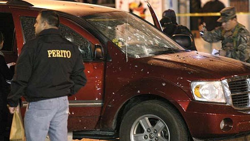 Policias ministeriales inspeccionan el vehículo del comandante acribillado.