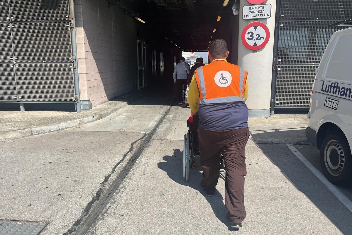 Un trabajador de 'Sin Barreras' acompaña a un viajero a recoger su maleta en El Prat.