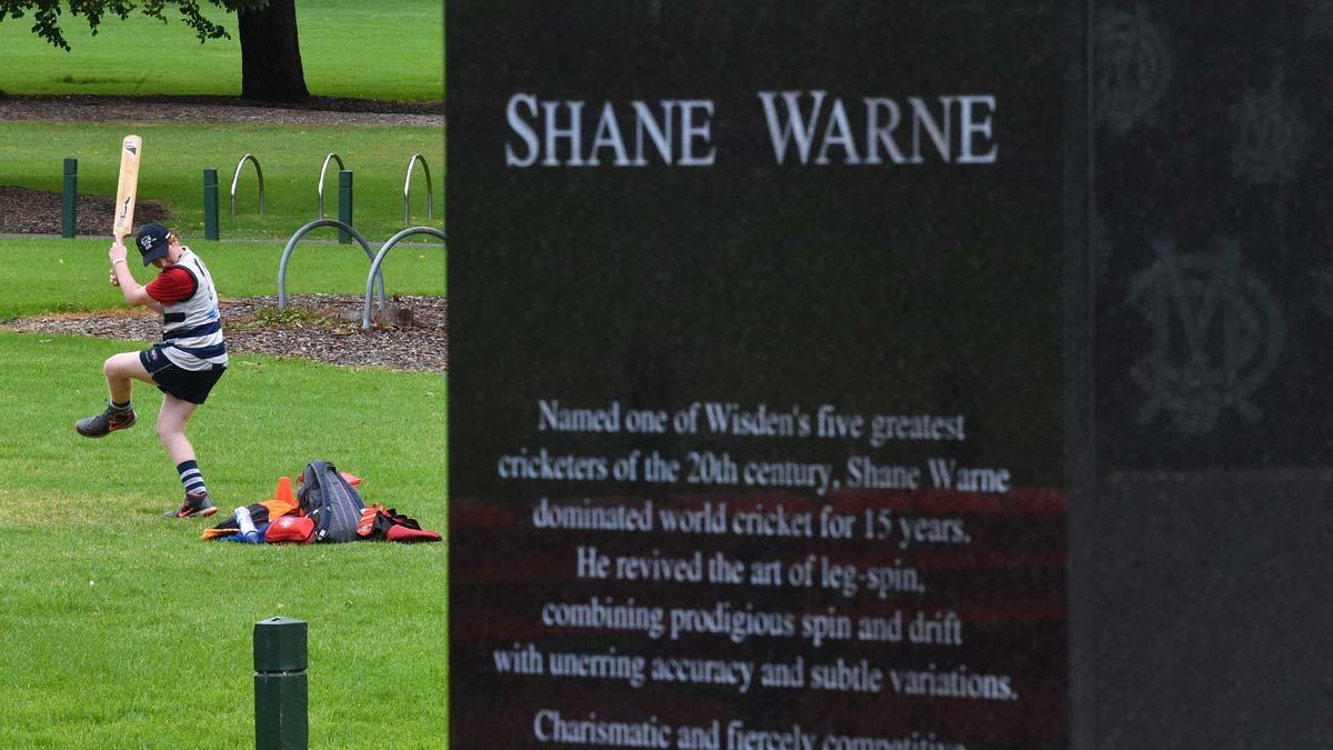 Un hombre juega a cricket junto a la estatua en homenaje a Shane Warne en Melbourne