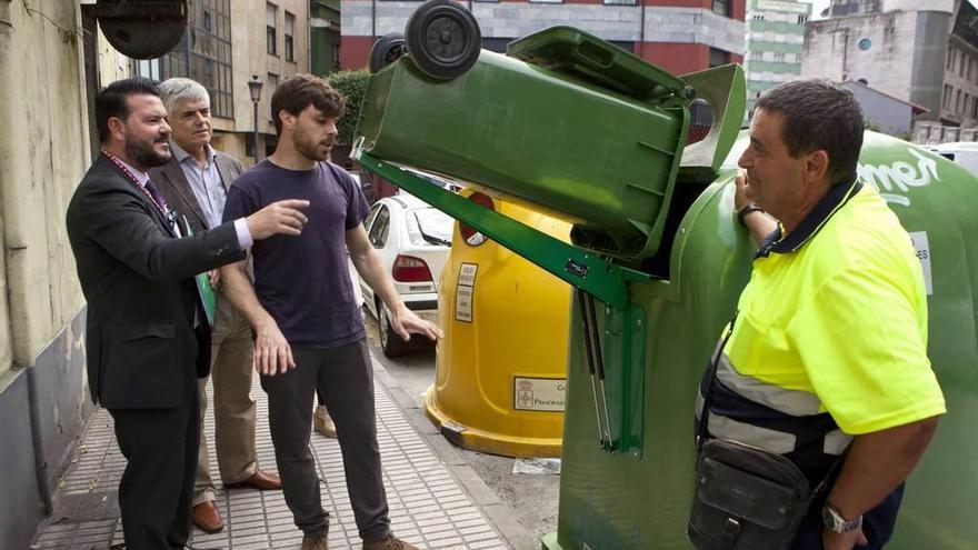 Germán Fernández, Santiago Fernández y el concejal Luis Baragaño prueban el sistema en un contenedor de vidrio instalado en una calle de Sama.