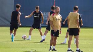 Hansi Flick departe con sus ayudantes durante un entrenamiento