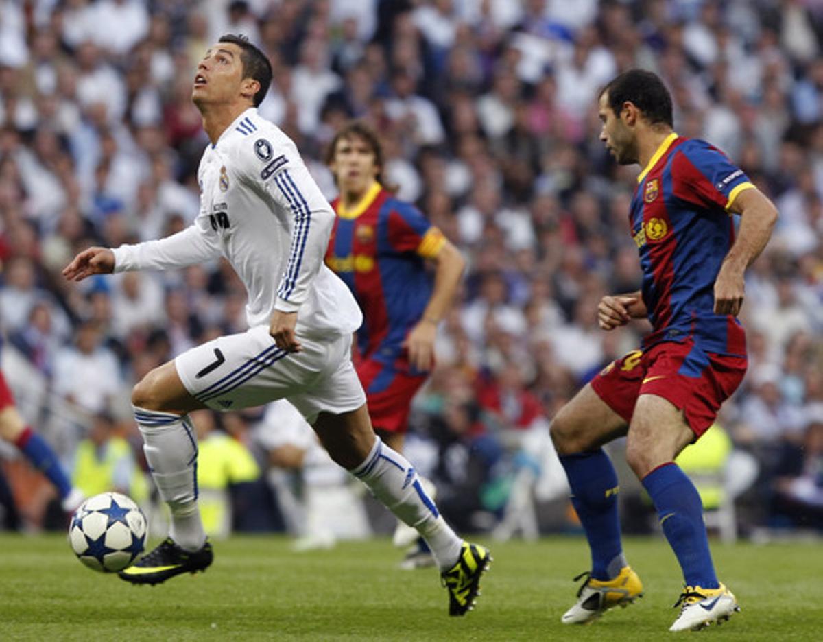 Cristiano Ronaldo controla la pilota davant la presència del centrecampista argentí del Barça Javier Mascherano.
