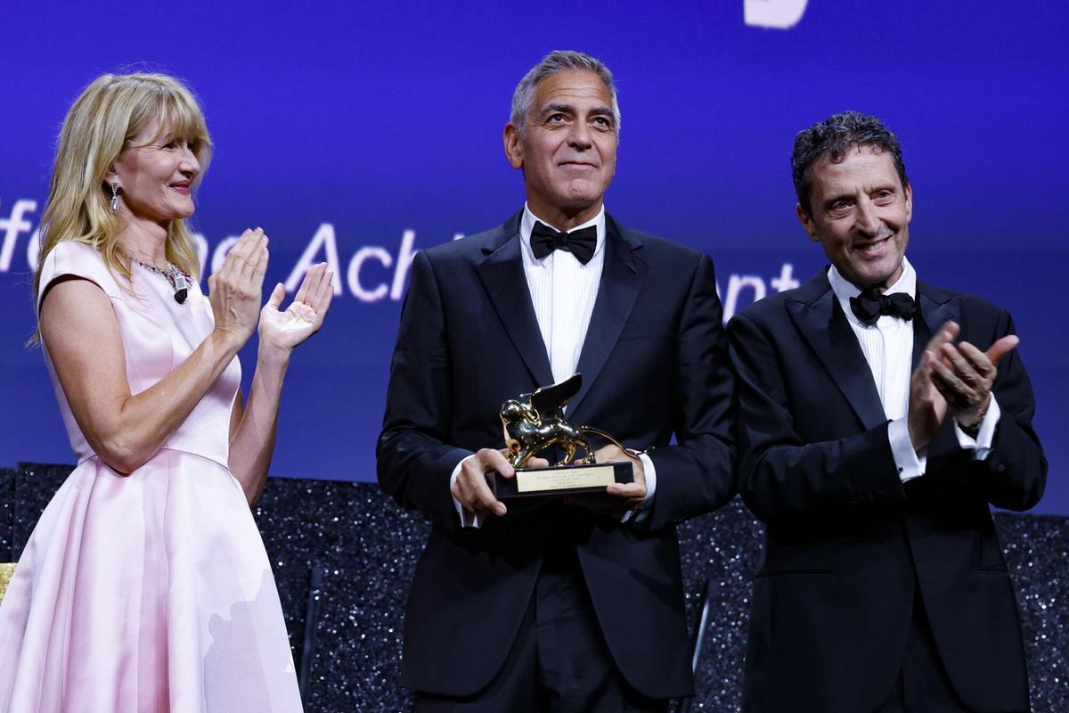 George Clooney recibe el Premio León de Oro de manos de la actriz estadounidense Laura Dern y del presidente de la Bienal, Pietrangelo Buttafuoco.